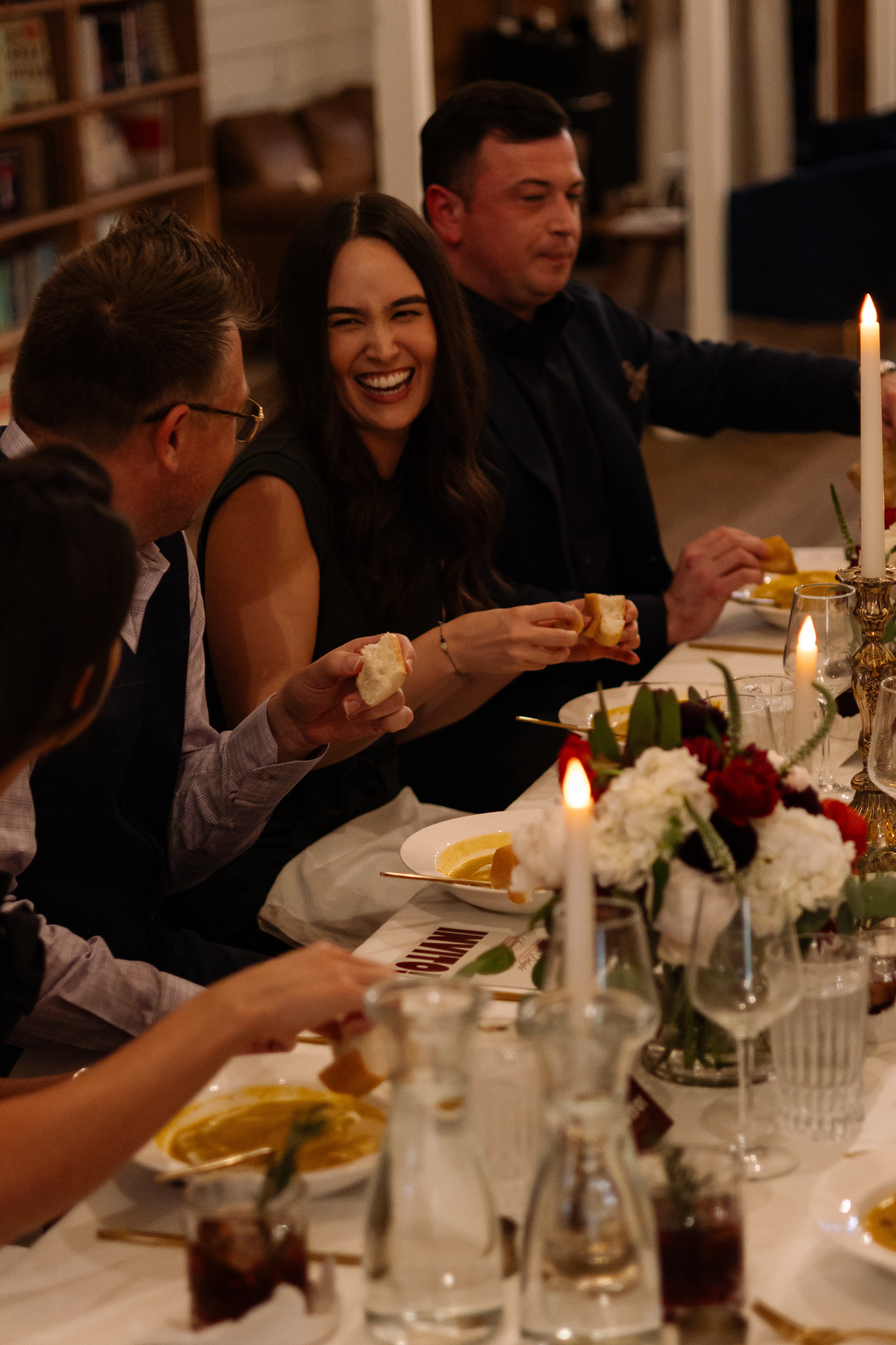 Well dressed woman and man at a dinner table laughing and talking together.